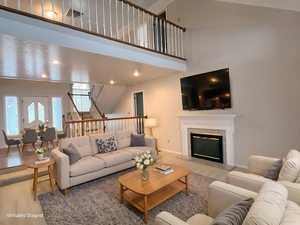 Living room featuring a high ceiling, a glass covered fireplace, and wood finished floors