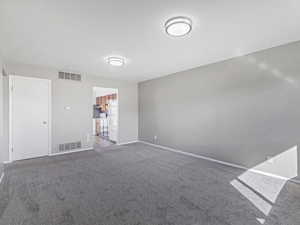 Unfurnished room featuring dark carpet and baseboards