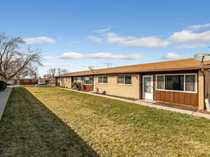 Rear view of property featuring a lawn, brick siding, and board and batten siding