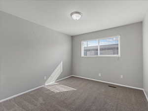 Empty room with dark carpet and baseboards