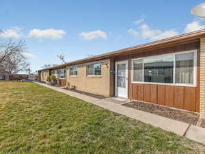 View of front of home with board and batten siding, a front lawn, and brick siding