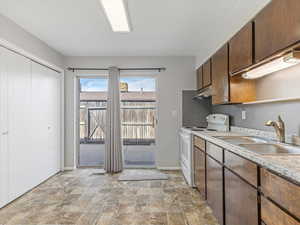 Kitchen featuring white range with electric stovetop, dark wood finish cabinets, stone finish flooring, light countertops, and open shelves