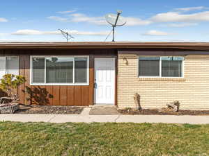 View of exterior entry featuring a yard, brick siding, and board and batten siding