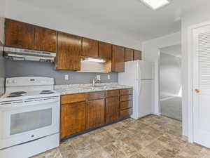 Kitchen featuring white appliances, stone finish floors, and light countertops