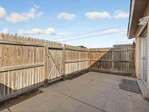 Fenced backyard featuring a patio area and a gate