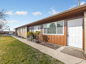 View of exterior entry with board and batten siding and a lawn