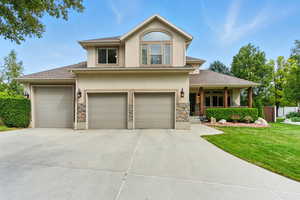 Traditional-style house with a shingled roof, driveway, a front lawn, covered porch, and stucco siding
