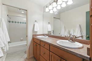 Full bath featuring double vanity, light tile patterned floors, and tub / shower combination