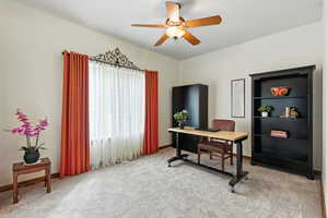 Home office featuring light carpet and ceiling fan