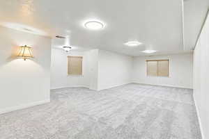 Spare room featuring light colored carpet and a textured ceiling
