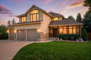 Traditional home featuring concrete driveway, stucco siding, an attached garage, and stone siding