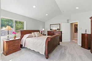 Bedroom with light carpet, vaulted ceiling, and recessed lighting