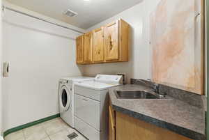 Laundry area with washer and clothes dryer, a textured ceiling, light tile patterned flooring, and cabinet space