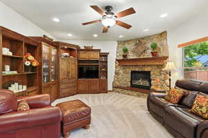 Living room featuring ceiling fan, light colored carpet, a stone fireplace, and recessed lighting