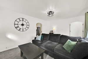 Carpeted living room featuring arched walkways and baseboards