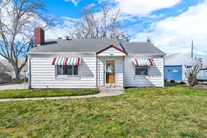 Bungalow-style home featuring a front lawn, a chimney, and a shingled roof