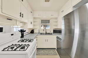 Kitchen featuring open shelves, stainless steel appliances, and light countertops
