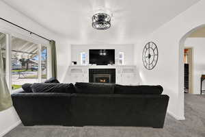 Carpeted living room with arched walkways and a tile fireplace