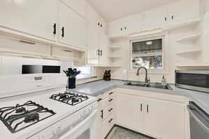Kitchen with open shelves, stainless steel appliances, white cabinets, and light countertops
