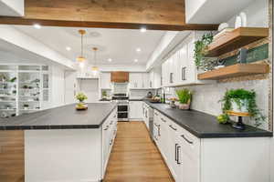 Gorgeous updated kitchen with white cabinets,  stunning solid surface countertops, stainless steel appliances and beautiful pendant lighting .