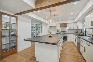 Gorgeous updated kitchen with white cabinets,  stunning solid surface countertops, stainless steel appliances and beautiful pendant lighting .