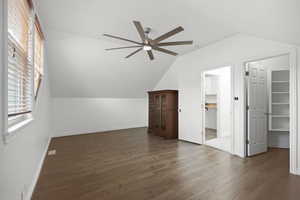 Bedroom with walk in closet, wood-look flooring and a ceiling fan