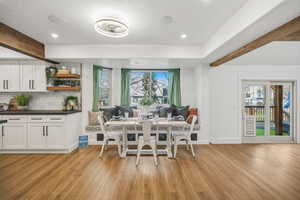 Dining area with built in banquette, wood-look flooring and recessed lighting