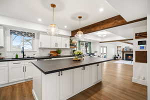 Gorgeous updated kitchen with white cabinets,  stunning solid surface countertops, stainless steel appliances and beautiful pendant lighting .