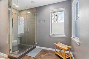 Full bath with a stall shower and dark tile patterned flooring