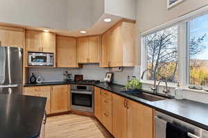 Kitchen featuring light wood finish cabinetry, stainless steel appliances, recessed lighting, light wood-style floors, and backsplash