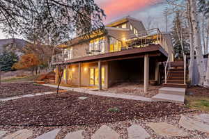 Back of property at dusk featuring stairs and a deck