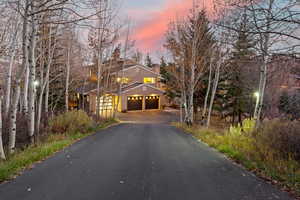 View of front of home featuring a chimney, stucco siding, a garage, and driveway