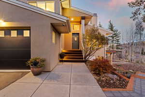 Exterior entry at dusk featuring stucco siding and a garage