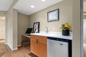 Bar area featuring dishwasher, light countertops, light wood finished floors, and recessed lighting