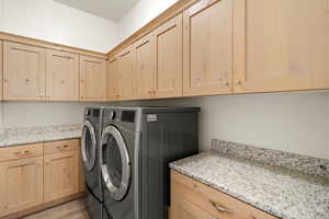 Laundry room featuring washer and clothes dryer, light wood-type flooring, and cabinet space