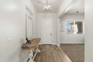 Entrance foyer with light wood finished floors and a chandelier