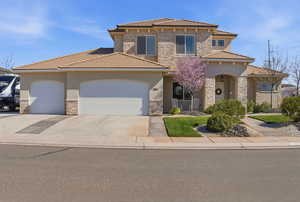 View of front facade featuring stone siding, an attached garage, stucco siding, and concrete driveway