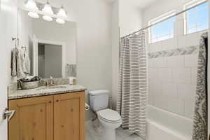 Bathroom featuring vanity, shower / bath combo, and light marble finish flooring
