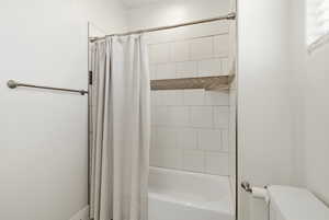 Bathroom featuring toilet and shower / bath combo with shower curtain