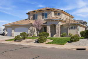 View of front of home featuring stone siding, stucco siding, a tiled roof, and a garage