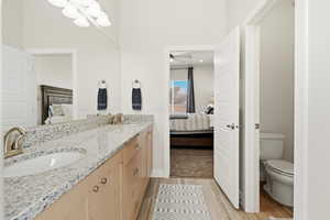Ensuite bathroom with double vanity and light wood-type flooring