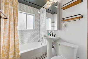 Bathroom with toilet and shower / bath combination with curtain