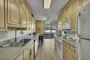 Kitchen with light wood finish cabinets, white appliances, light wood finished floors, and light countertops