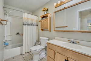 Bathroom featuring vanity, shower / bath combo, and light tile patterned floors