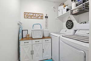 Laundry area featuring separate washer and dryer and cabinet space