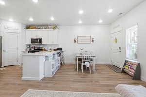 Kitchen with white cabinets, recessed lighting, light wood finished floors, a peninsula, and stainless steel appliances