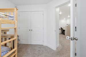 Bedroom featuring an office area, light colored carpet, and a closet