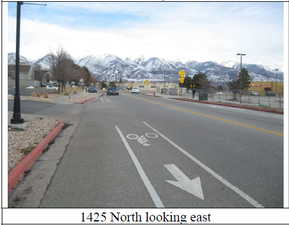 View of asphalt road featuring curbs, a mountain view, and sidewalks
