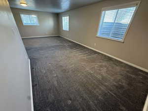 Unfurnished room with dark colored carpet and plenty of natural light