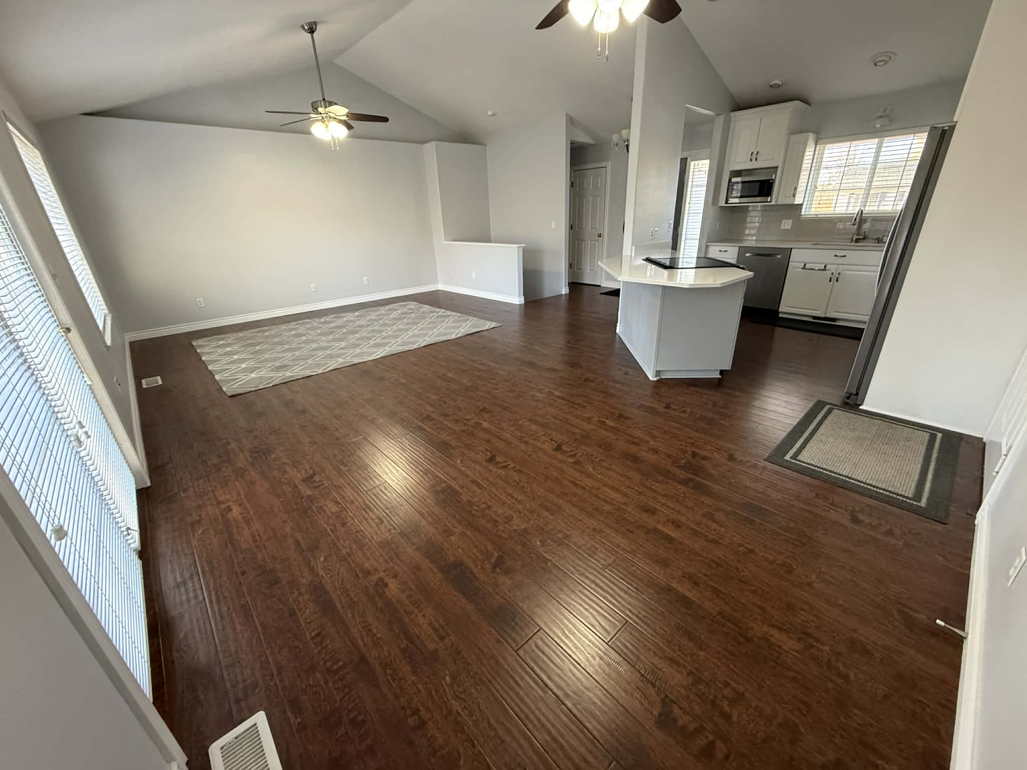 Unfurnished living room with ceiling fan and dark wood-style flooring